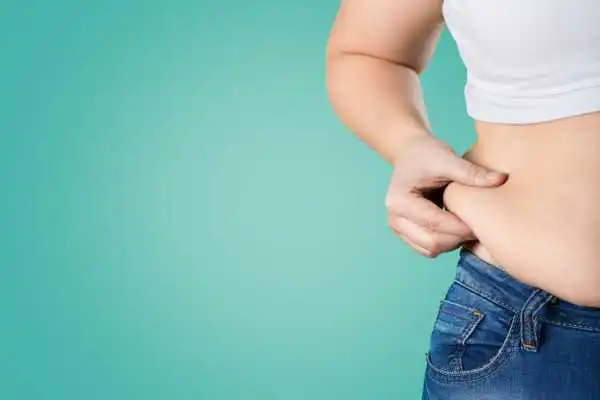 Image of woman pinching her love handles to show weight gain West Malling
